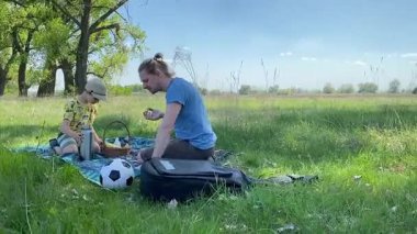 Küçük baba ve oğlu yaz pikniğinin tadını çıkarıyor, birlikte güzel vakit geçiriyorlar. Dışarıdaki eğlenceli aktivitelere katılıyorlar, sıcak güneşin altında mutlu anılar yaratıyorlar.