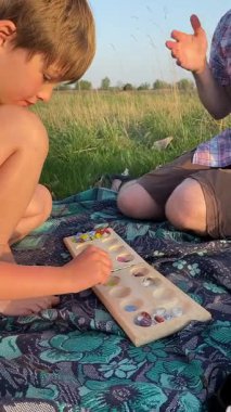 Genç bir baba ve oğlunun yaz pikniğini otlakta birlikte geçirdiği dikey görüntüler. Dışarıdaki eğlenceli aktivitelere katılıyorlar, sıcak güneşin altında mutlu anılar yaratıyorlar.