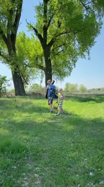 Genç bir baba ve oğlunun yaz pikniğini otlakta birlikte geçirdiği dikey görüntüler. Dışarıdaki eğlenceli aktivitelere katılıyorlar, sıcak güneşin altında mutlu anılar yaratıyorlar.