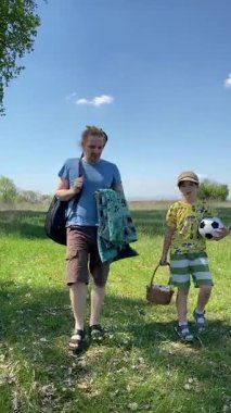 Genç bir baba ve oğlunun yaz pikniğini otlakta birlikte geçirdiği dikey görüntüler. Dışarıdaki eğlenceli aktivitelere katılıyorlar, sıcak güneşin altında mutlu anılar yaratıyorlar.