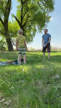 Genç bir baba ve oğlunun yaz pikniğini otlakta birlikte geçirdiği dikey görüntüler. Dışarıdaki eğlenceli aktivitelere katılıyorlar, sıcak güneşin altında mutlu anılar yaratıyorlar.