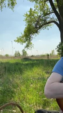 Genç bir baba ve oğlunun yaz pikniğini otlakta birlikte geçirdiği dikey görüntüler. Dışarıdaki eğlenceli aktivitelere katılıyorlar, sıcak güneşin altında mutlu anılar yaratıyorlar.