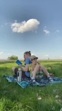 Genç bir baba ve oğlunun yaz pikniğini otlakta birlikte geçirdiği dikey görüntüler. Dışarıdaki eğlenceli aktivitelere katılıyorlar, sıcak güneşin altında mutlu anılar yaratıyorlar.