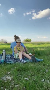 Genç bir baba ve oğlunun yaz pikniğini otlakta birlikte geçirdiği dikey görüntüler. Dışarıdaki eğlenceli aktivitelere katılıyorlar, sıcak güneşin altında mutlu anılar yaratıyorlar.