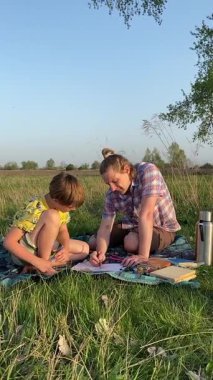 Genç bir baba ve oğlunun yaz pikniğini otlakta birlikte geçirdiği dikey görüntüler. Dışarıdaki eğlenceli aktivitelere katılıyorlar, sıcak güneşin altında mutlu anılar yaratıyorlar.