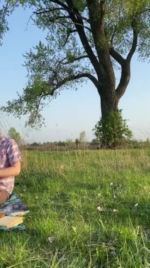 Genç bir baba ve oğlunun yaz pikniğini otlakta birlikte geçirdiği dikey görüntüler. Dışarıdaki eğlenceli aktivitelere katılıyorlar, sıcak güneşin altında mutlu anılar yaratıyorlar.