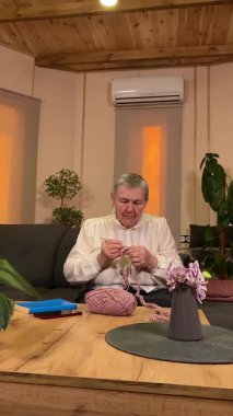 Dikey yaşlı bir kadın evde boş vaktinin tadını çıkarıyor, rahat bir oturma odasında rahatlatıcı bir hobi ediniyor. Etrafı konforla çevriliyken günlük rutininde ve en sevdiği meşgalesinde neşe ve huzur bulur. 