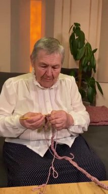 Dikey yaşlı bir kadın evde boş vaktinin tadını çıkarıyor, rahat bir oturma odasında rahatlatıcı bir hobi ediniyor. Etrafı konforla çevriliyken günlük rutininde ve en sevdiği meşgalesinde neşe ve huzur bulur. 