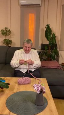 Dikey yaşlı bir kadın evde boş vaktinin tadını çıkarıyor, rahat bir oturma odasında rahatlatıcı bir hobi ediniyor. Etrafı konforla çevriliyken günlük rutininde ve en sevdiği meşgalesinde neşe ve huzur bulur. 