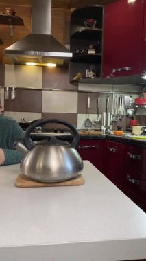 Dikey yaşlı kadın sıcak bir ev mutfağında öğle yemeği yiyor, sıcak bir ev yemeği yiyor. Yavaş ve dikkatli bir şekilde yiyor, tanıdık yiyeceklerin rahatlığını ve etrafındaki sakin atmosferi takdir ediyor.. 