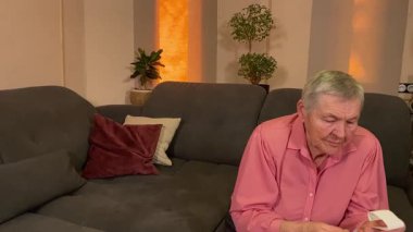 Oturma odasında vergileri, elektrik faturalarını akıllı telefon ve abaküs kullanarak hesap yapan yaşlı bir kadın. Odaklanmış ve düşünceli. Ekonomisini hem modern hem de geleneksel araçlarla yönetiyor. 