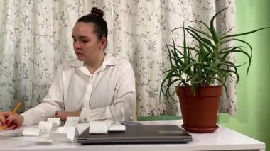 İş elbiseli genç bir kadın ev ofisinde çalışıyor, dizüstü bilgisayar ve telefon kullanıyor. Odaklanmış ve profesyonel olarak, günlük rutininde teknoloji ve iletişimi birleştirerek görevleri etkili bir şekilde yönetiyor. 