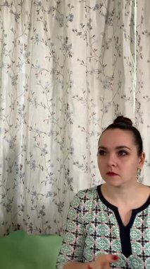 Dikey olarak, bir kadının odak ve özenle yüzüne makyaj yapması ve kapalı bir masada oturması. Evde ayna ve çeşitli kozmetik ürünler kullanarak kişisel güzellik rutininin bir parçası olarak görünüşünü geliştiriyor.