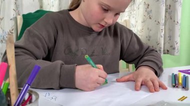 Genç kız evde yaratıcı aktiviteler yapıyor, hobisinin bir parçası olarak kalemlerle resim çiziyor. Odaklanmış ve ilham almış, sanatsal ifadenin günümüze getirdiği eğlence ve rahatlıktan zevk alıyor.. 