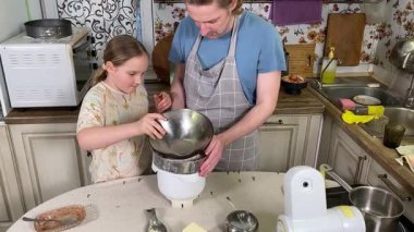 Önlüklü genç baba ve küçük kızı mutfakta birlikte yemek pişiriyorlar. Aile tatillerini paylaşırlar, yemek hazırlama ve sıcak bir yuva ortamında eğlenceli etkileşimlerle eğlenirler.