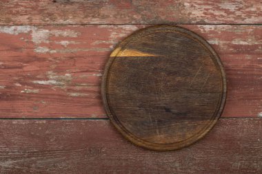 Kırmızı ahşap bir masada daire şeklinde kesme tahtası. Yemek hazırlama aleti ve mutfak aletleri. Metin için boşluk.