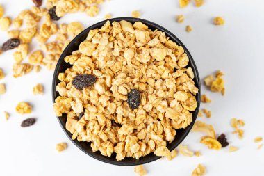 Granola bowl with raisins, nuts. Homemade crunchy granola scattered on white background, top view. Healthy eating. 