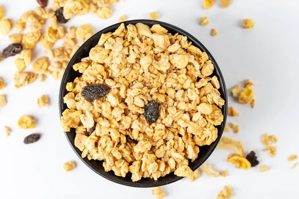 Granola bowl with raisins, nuts. Homemade crunchy granola scattered on white background, top view. Healthy eating.