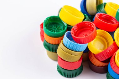 Farklı renk şişe kapakları, geri dönüşüm için mükemmel hammadde. Beyaz üzerine izole edilmiş plastik şişe ve kapaklı kompozisyon.