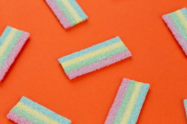 Turuncu arka planda bir sürü renkli jöle şekeri var. Tatlı yemek tatlısı. Mesaj için yer var. Üst görünüm.