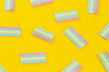 Sarı arka planda bir sürü renkli jöle şekeri var. Tatlı yemek tatlısı. Mesaj için yer var. Üst görünüm.