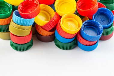 Farklı renk şişe kapakları, geri dönüşüm için mükemmel hammadde. Beyaz üzerine izole edilmiş plastik şişe ve kapaklı kompozisyon.