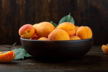 Delicious ripe apricots in a clay bowl on the table close-up. Delicious fruits.