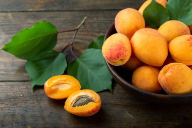 Delicious ripe apricots in a clay bowl on the table close-up. Delicious fruits.