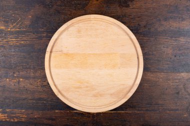 Round blank pizza board on a wooden background. View from above