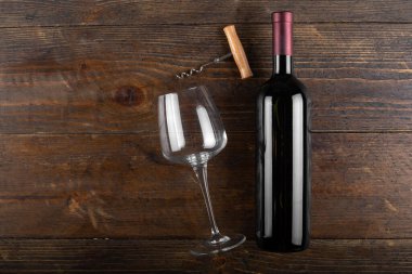 Bottle with red wine, glass and corkscrew, on a wooden background. View from above
