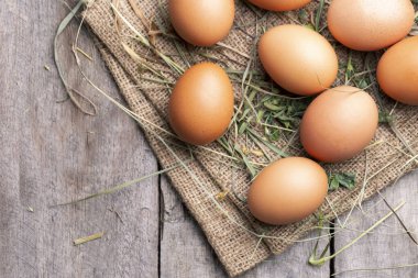 Esmer tavuk yumurtaları saman ve eski tahtaların arkasında yatar. Çiftçilik kavramı.