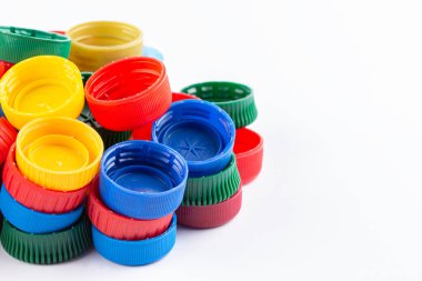 Farklı renk şişe kapakları, geri dönüşüm için mükemmel hammadde. Beyaz üzerine izole edilmiş plastik şişe ve kapaklı kompozisyon.