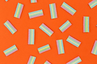 Turuncu arka planda bir sürü renkli jöle şekeri var. Tatlı yemek tatlısı. Mesaj için yer var. Üst görünüm.