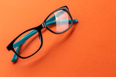 Turuncu arka planda görüş için gözlük. Optik mağaza, gözlük seçimi, göz testi, göz doktorunda vizyon muayenesi, moda aksesuarları konsepti.