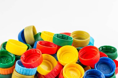 Farklı renk şişe kapakları, geri dönüşüm için mükemmel hammadde. Beyaz üzerine izole edilmiş plastik şişe ve kapaklı kompozisyon.