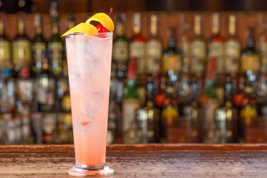 Barda muhteşem bir alkollü kokteyl. Bol buzlu pembe bir içecek, ve güzel bir limon kabuğu ve kiraz.