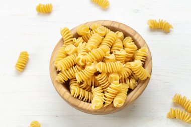 Wooden Bowl 'daki çiğ Pasta Fusilli Beyaz Rustik Arka plan' da. Metin için boşluk.