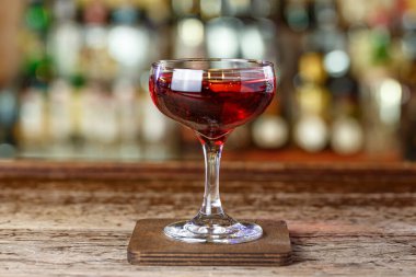 Cin ve vermuta dayalı bir aperatif Martinez, alkollü şişelerin bulanık arka planında barın üzerinde bir kokteyl duruyor.