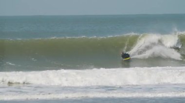 Dalgalarda sörf yapan bir adamın yavaş çekim videosu.