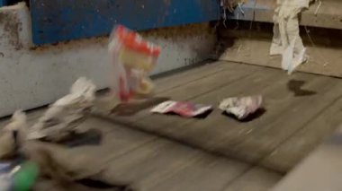 Plastik ve kağıt atıkları bir taşıma bandında sıralanmıştır