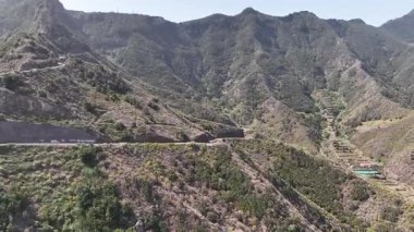 Tenerife dağlarının insansız hava aracı videosu ve yol kenarındaki kayalık bir tepe.
