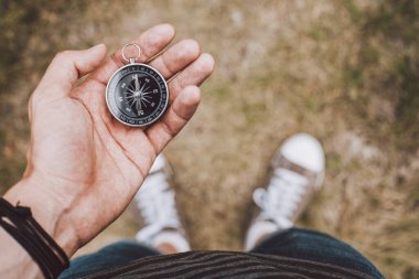 Hipster traveler holding compass in hand