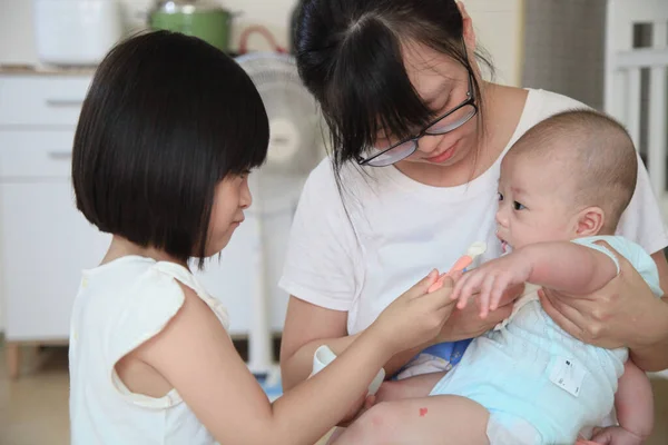 愛する家族のシーンで赤ちゃんを養うのに役立つアジアの兄弟姉妹 — ストック写真
