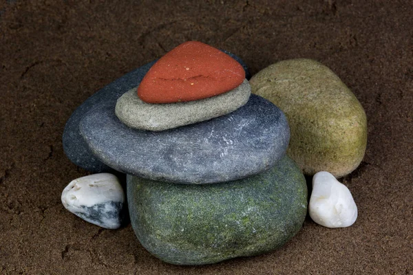 Verschiedene Felsen Und Kieselsteine Auf Einem Nassen Sandstrand Aufgetürmt — Stockfoto