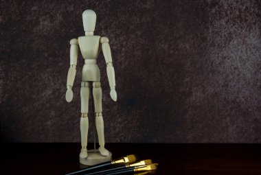 Sanatçılar manken ahşap figürler ve sanatçılar parlak ahşap bir yüzeye fırçalarlar.