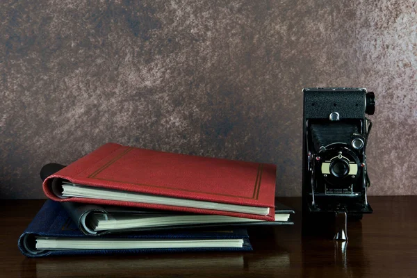 Old folding camera and photo albums on a varnished wooden surface