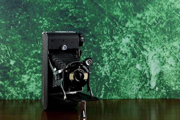 Old folding film camera on a polished wooden shelf