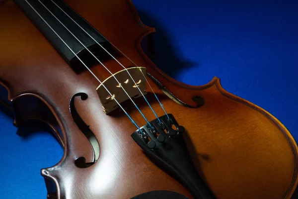 バイオリン本体部分的に青いテーブルの上に点灯 — ストック写真
