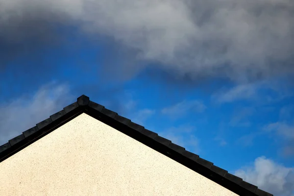 House roof apex against a blue cloudy sky