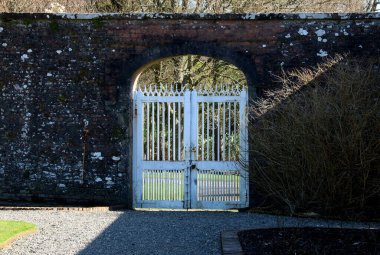 Duvarlarla çevrili bir kır evinin eski bahçe kapısı.